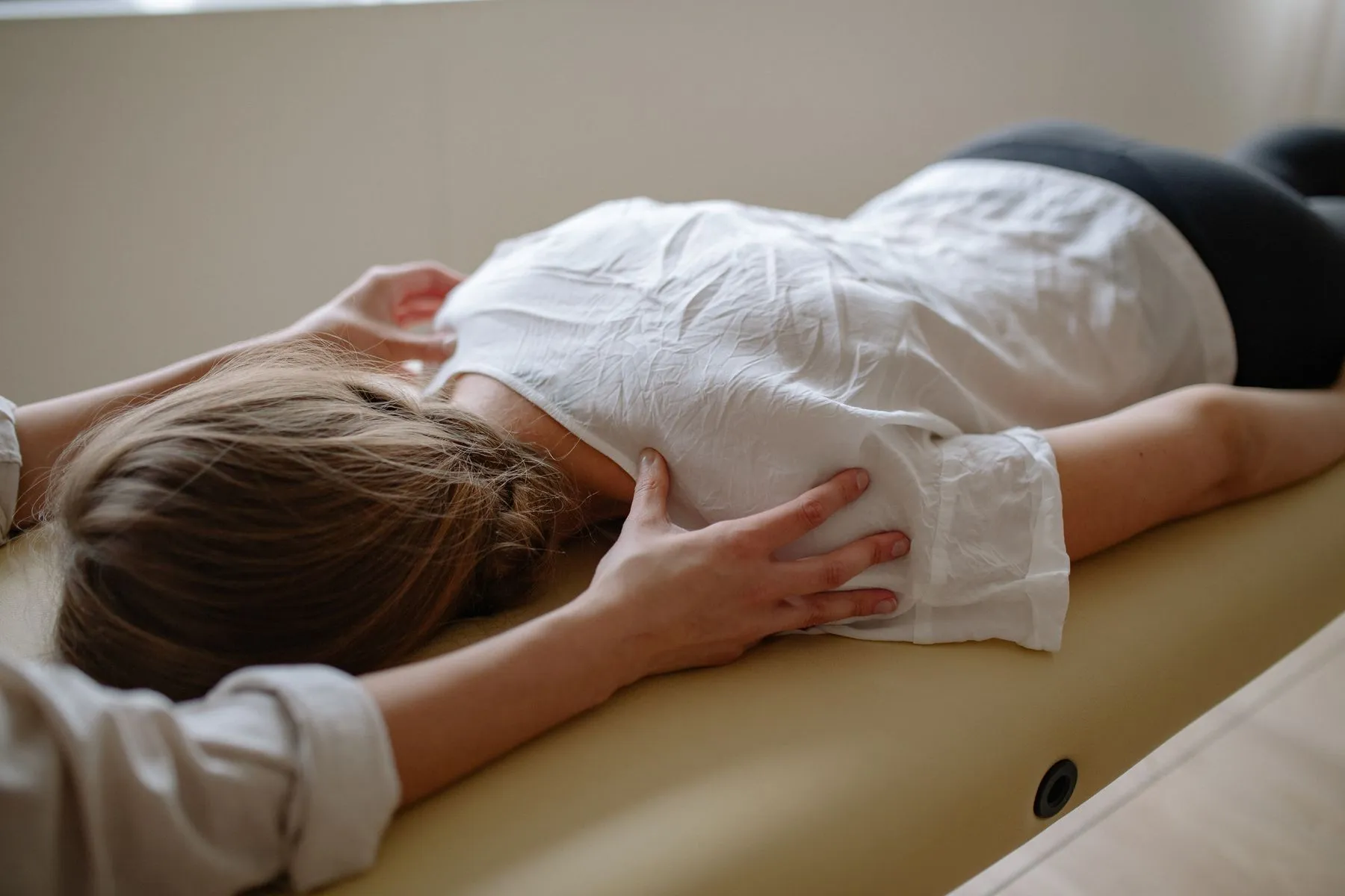 Fisioterapeuta tratando la espalda de una paciente tumbada en la camilla